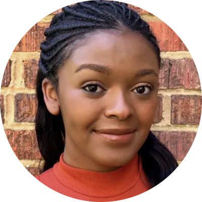 headshot of staff with dark braided hair wearing a coral turtleneck